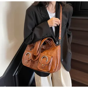 Close-up of retro brown PU leather tote bag with large metal rings and external pockets