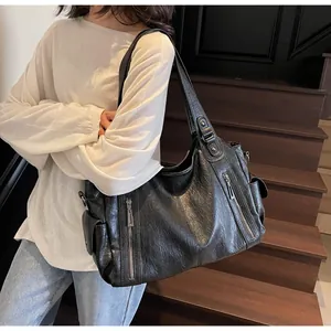 Close-up of black retro leather tote bag with functional zippers and wrinkled texture