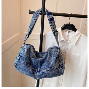 Close-up of blue washed denim hobo bag on a hanger with adjustable wide shoulder strap