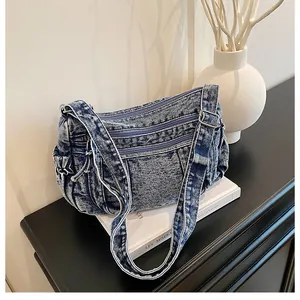 Close-up of vintage washed denim shoulder bag with multiple functional zipper pockets