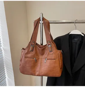 Detail van bruine PU-lederen shopper met functionele ritsen en zilveren metalen gespen