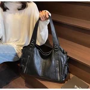 Detail of black tote bag with wrinkled faux leather texture and metallic zippers