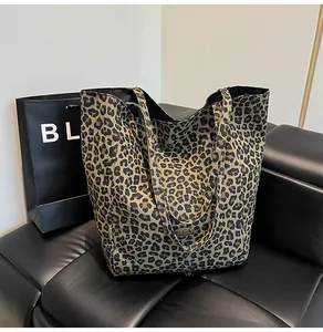Detail of metal handmade tag on leopard print canvas tote bag over black leather background