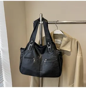 Detail van zwarte kunstlederen tote bag met metalen gespen en ritszakken op de tas