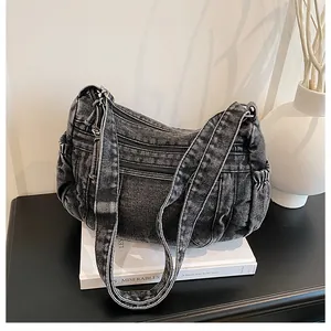 Detailed view of the dark grey denim shoulder bag with multiple functional zip pockets