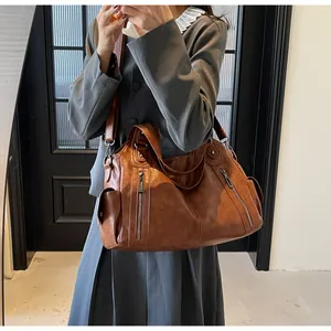 Close-up of vintage brown leather tote bag showing pocket details and soft texture