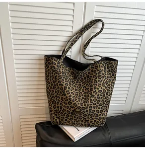 Detailed macro shot of the golden oval metal logo plate on leopard print canvas tote bag