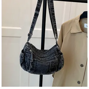 Detail of washed black denim crossbody bag featuring multiple zippers and Y2K vintage style