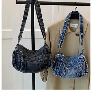 Detail of vintage denim crescent crossbody bags with multiple zippers in blue and grey