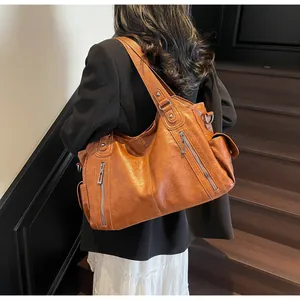 Detail of retro brown tote bag showing pebbled leather texture and silver zipper pockets