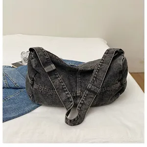 Close-up of vintage washed black denim crossbody bag with adjustable wide strap