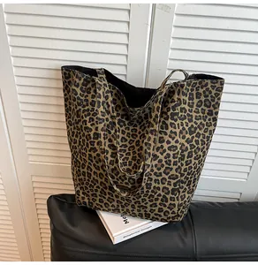 Detail of a large leopard print canvas tote bag with black lining on a sleek black stand