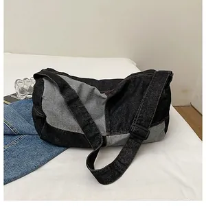 Close-up of color-block denim messenger bag with adjustable wide strap on white bedding