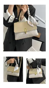 Detail of woven texture handbag with gold buckle and heart print silk scarf on handle