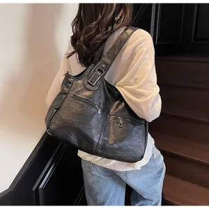 Detail van grote zwarte shopper met meerdere ritsen en metalen hardware gedragen door model