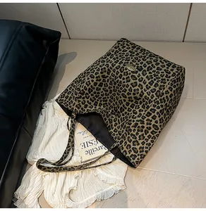 Detail of leopard print tote bag with metal logo plaque on textured canvas material