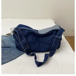 Detail of dark blue denim tote bag featuring contrast stitching and wide adjustable strap