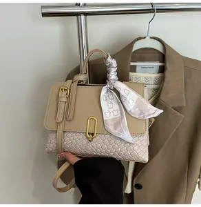 Detail of beige woven handbag with gold U-buckle and bear print scarf wrap handle