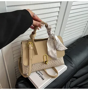 Close-up of beige woven tote bag with a patterned silk scarf and gold metal buckle detail