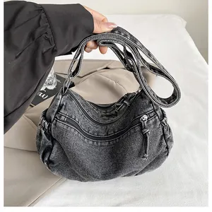 Close-up of charcoal grey denim shoulder bag featuring multiple functional zippers