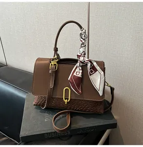 Detail of vintage woven handbag with dark brown leather, gold lock and silk scarf decor
