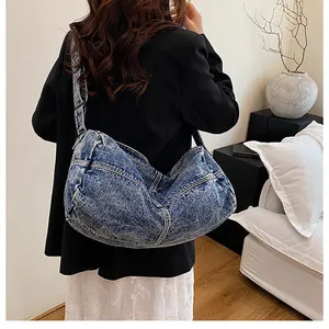 Close-up of light wash denim hobo bag featuring white contrast stitching and wide strap
