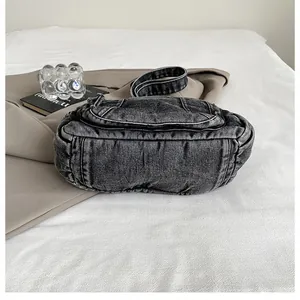 Detail of vintage washed denim shoulder bag with multiple pockets and natural texture