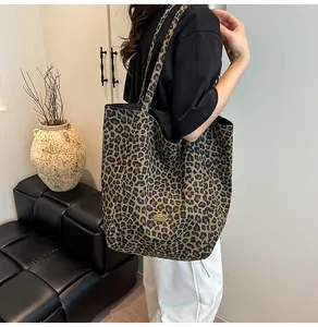 Detail of leopard print canvas tote bag featuring an oval handmade metal nameplate