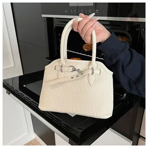 Detail van crème draagtas met verticale streeptextuur en decoratieve metalen gesp