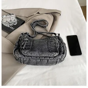 Detail of grey denim dumpling bag with pockets on a styled minimalist background