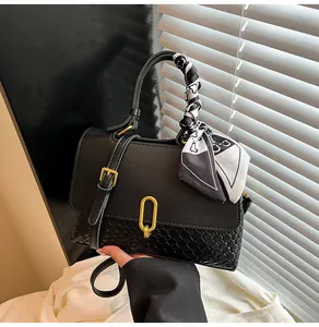 Detail of black woven leather handbag with gold U-buckle and decorative silk scarf