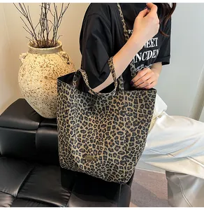 Detail of leopard print canvas tote bag with circular metal emblem and thick fabric texture
