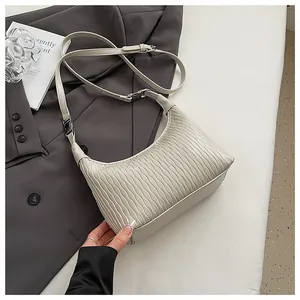 Detail der hellbeigen Plissee-Schultertasche mit vertikaler Wellenstruktur und Silberschnalle