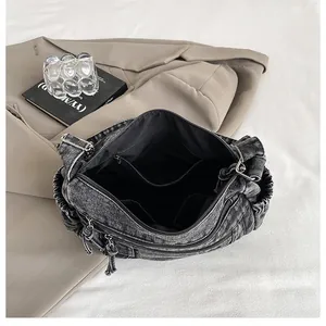 Detail of spacious interior with zipper pocket in washed denim dumpling shoulder bag