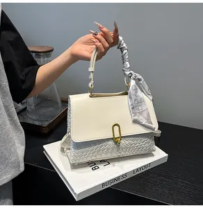 Detail of white woven handbag with silk scarf wrapped handle and gold twist lock