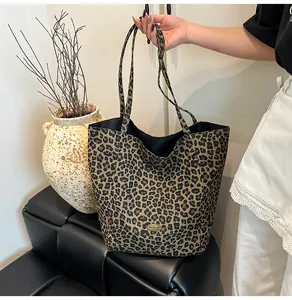 Detail of leopard print tote bag with golden metal tag and black inner lining