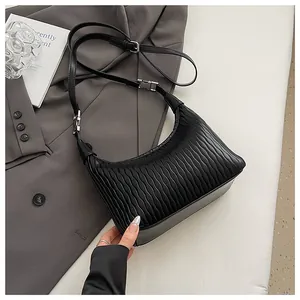 Detail der schwarzen Plissee-Schultertasche mit Silber-Hardware und Trageriemen auf Sakko
