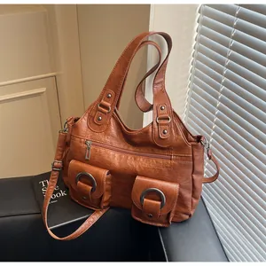 Detail of brown leather tote featuring large metal rings and textured front pockets