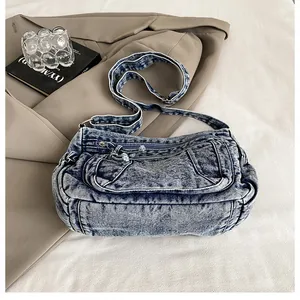 Detail of retro washed denim shoulder bag featuring front pockets and adjustable strap