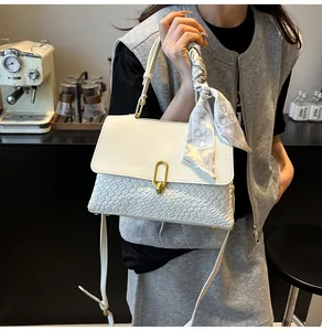 Detail of white handbag with woven texture, golden buckle, and decorative bear silk scarf
