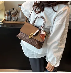 Detail of woven brown handbag with gold U-clasp and decorative silk scarf handle