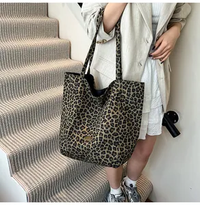 Close-up of leopard print canvas tote bag with a golden metal logo plate on the front