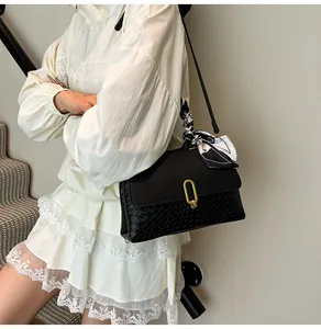 Detail of black woven texture handbag featuring a gold metal lock and printed silk scarf