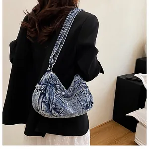 Rear view of a model wearing a vintage washed denim dumpling bag with multi-zipper details