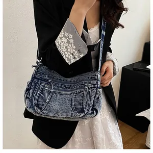 Detail of vintage washed denim crossbody bag featuring multiple functional zipper pockets