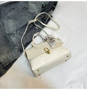Close-up of cream woven bag with crocodile pattern, floral silk scarf, and gold metal lock