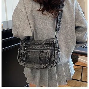 Detail of vintage washed denim crossbody bag with multiple zip pockets and wide strap
