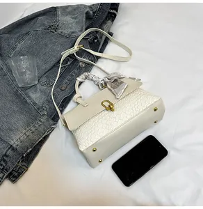 Detail of cream white woven handbag with golden buckle and decorative silk scarf