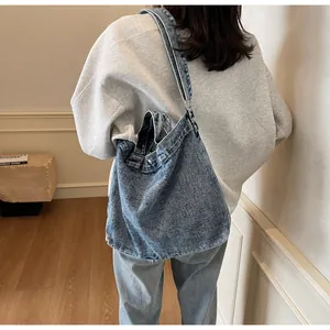 Side view of a vintage blue washed denim tote bag worn by a model in a minimal setting