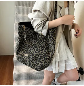 Detail view of large leopard print tote bag with metallic logo on textured canvas fabric